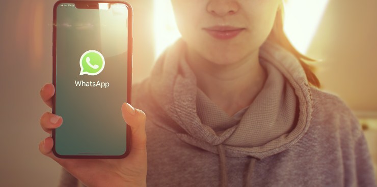 Donna con telefono in mano el'app WhatsApp