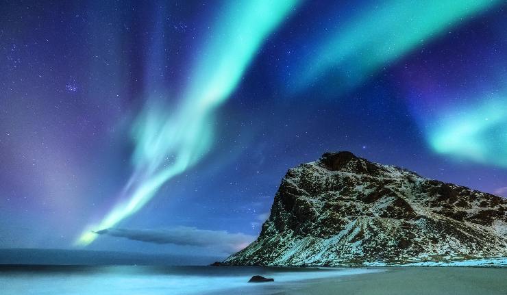 Aurora boreale blu su una montagna vicino al mare