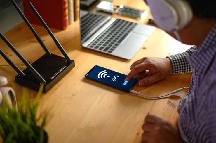 Uomo con le cuffie usa lo smartphone vicino a un router wifi