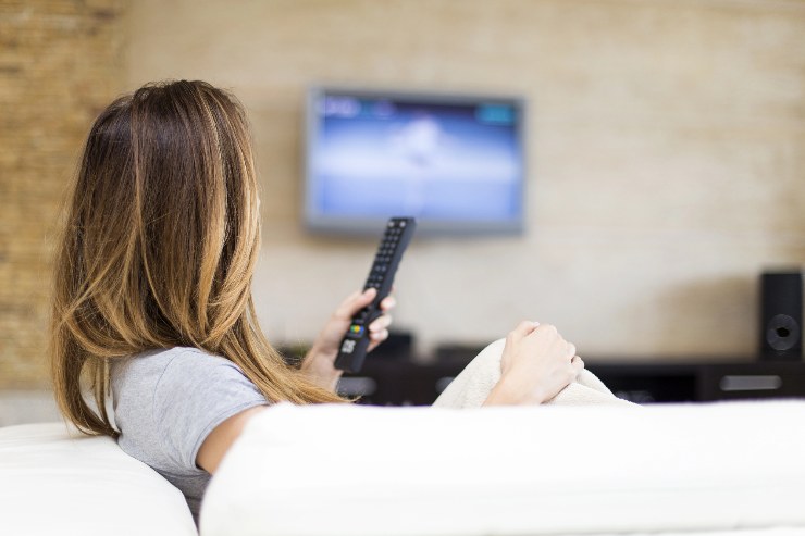 Donna guarda la TV con un telecomando in mano