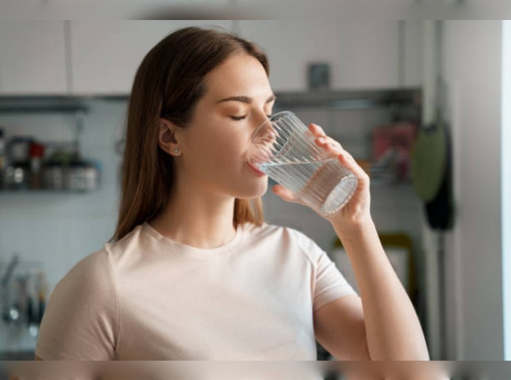 Giovane donna beve acqua da un bicchiere