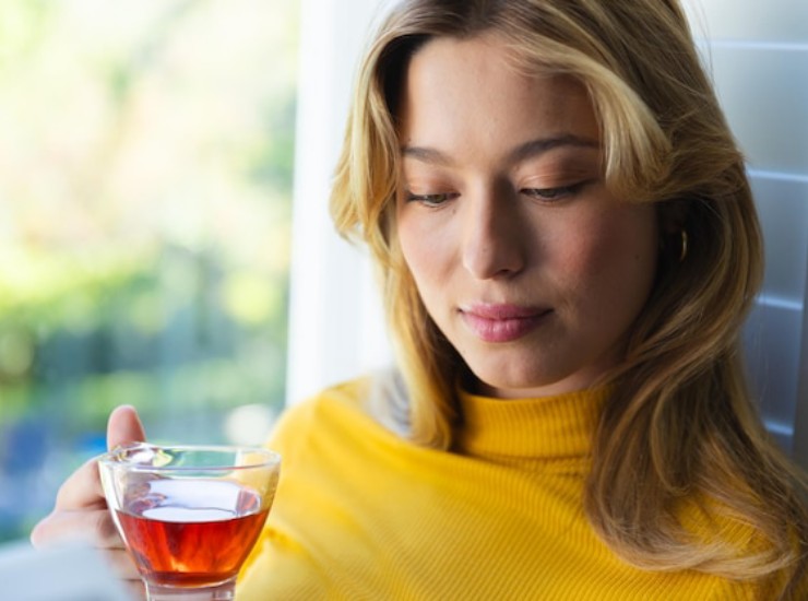 Una giovane ragazza bionda beve una tisana