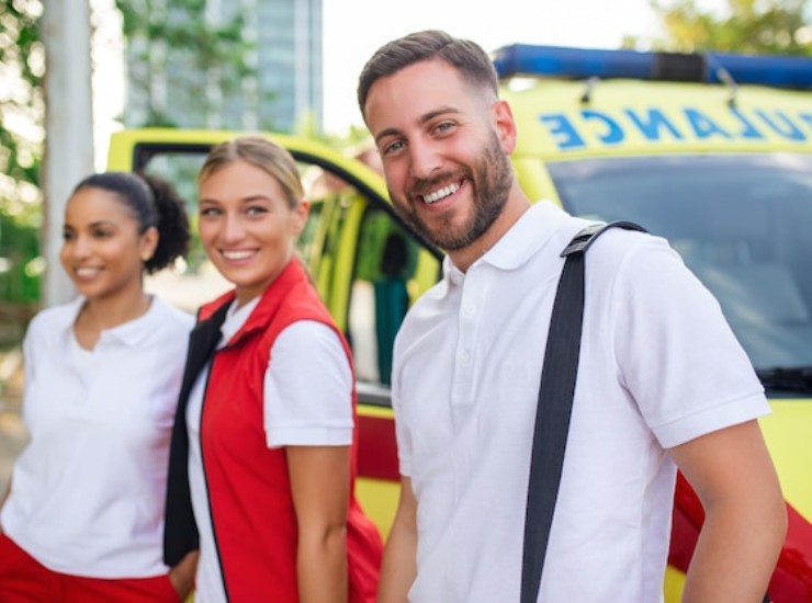 Giovani paramedici sorridenti davanti all'ambulanza