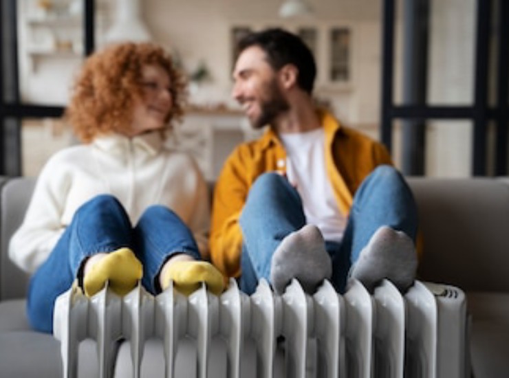 Una coppia siede felice con i piedi sul termosifone