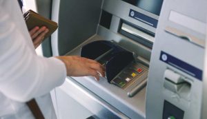 Persona davanti a un Bancomat digita il PIN della carta