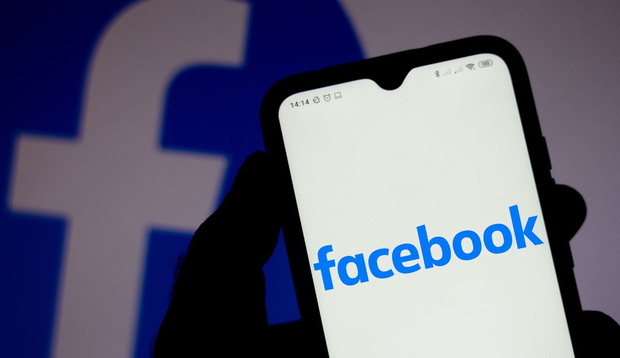 Mano di perosna con uno smartphone con il logo di Facebook