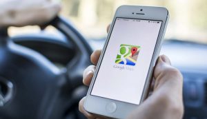 Persona alla guida con in mano uno smartphone con Google Maps