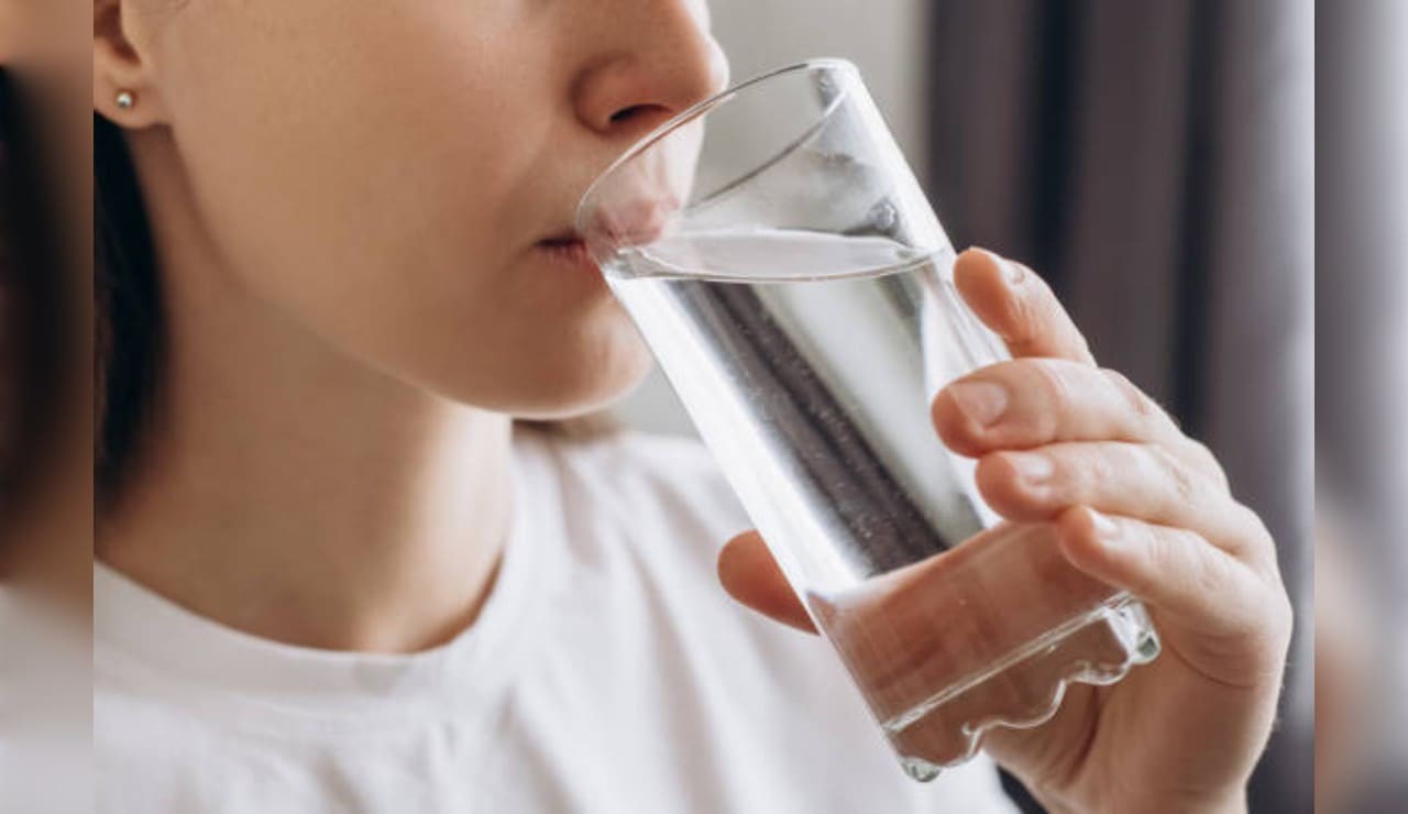 Donna beve acqua minerale da un bicchiere